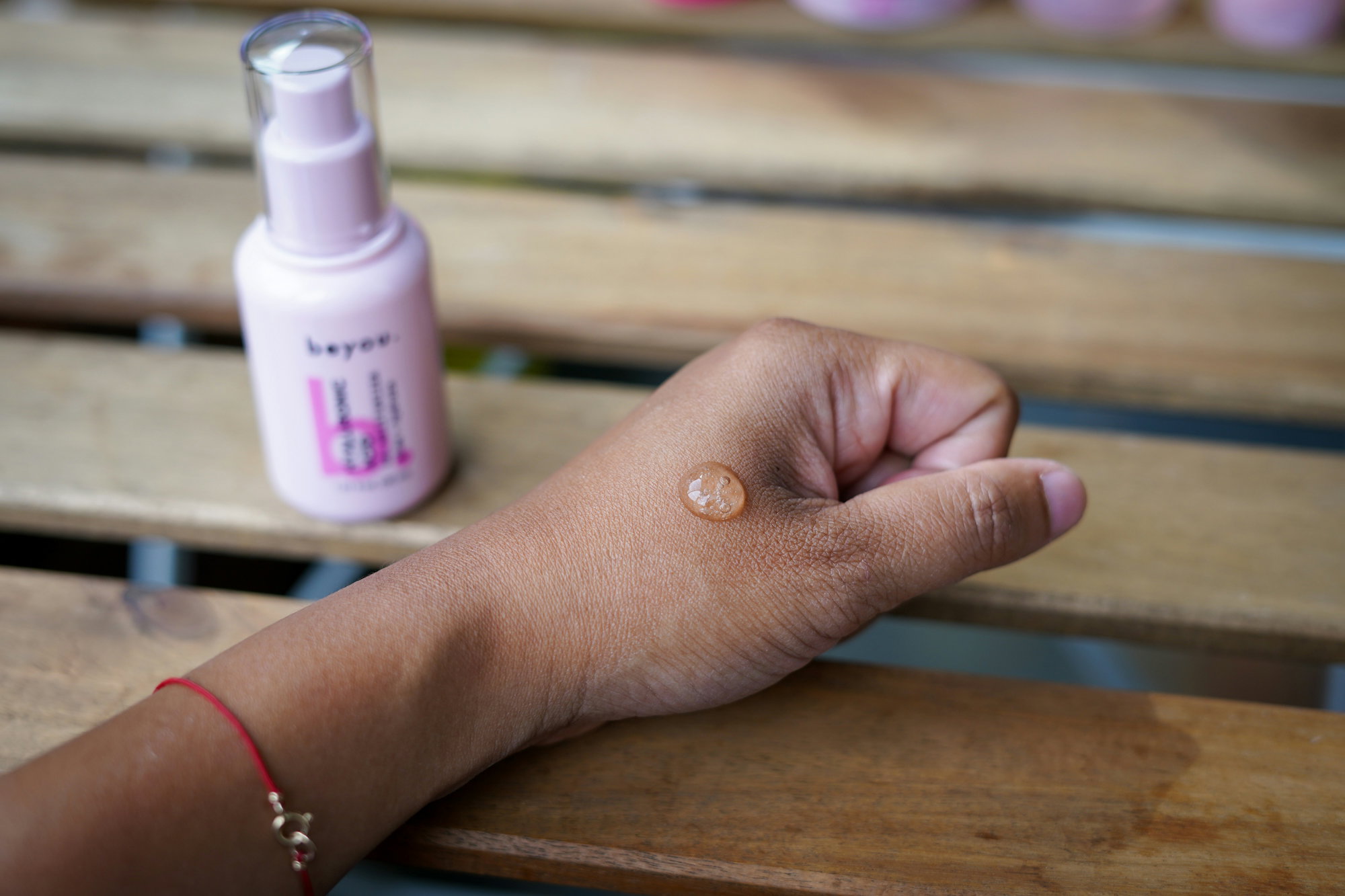 a-woman-s-hand-holding-a-bottle-of-sunscreen-on-a-wooden-bench.jpg a woman's hand holding a bottle of sunscreen on a wooden bench